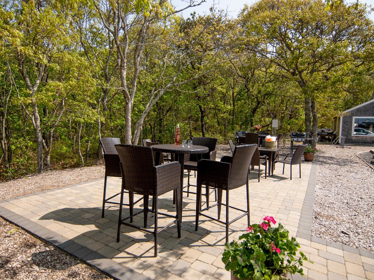 A patio area with outdoor furniture and a grill surrounded by trees.