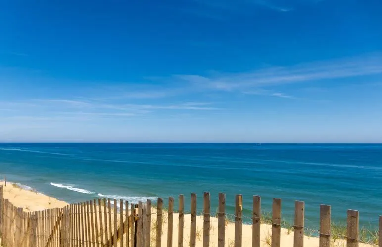 a beach scene with a wooden fence in the foreground