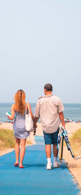 A couple walking toward the beach with folding chair