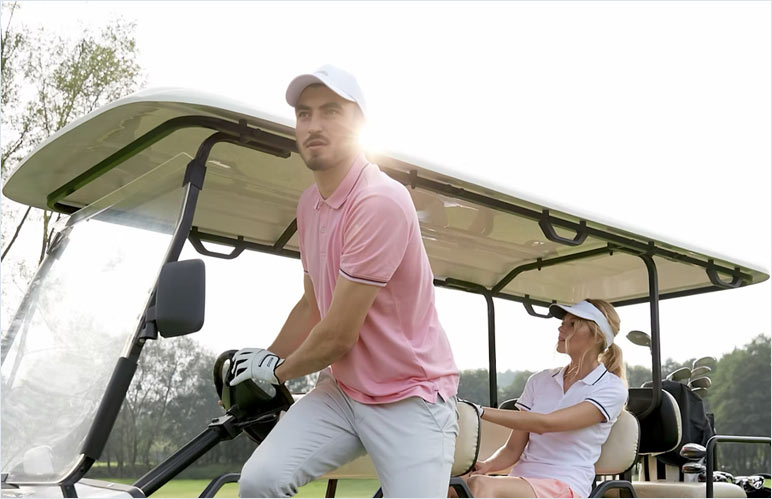 Male golfer stepping out of a golf cart while a female golfer remains seated