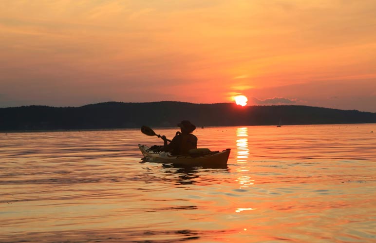 Sunset silhouette of a person in a canoe